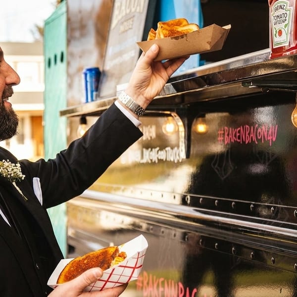 Man in a suit smiles while receiving food from a black food truck.